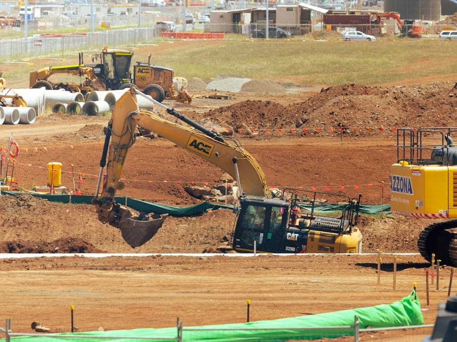 A tracked excavator parked on an open field of turned soil at a clearing site.