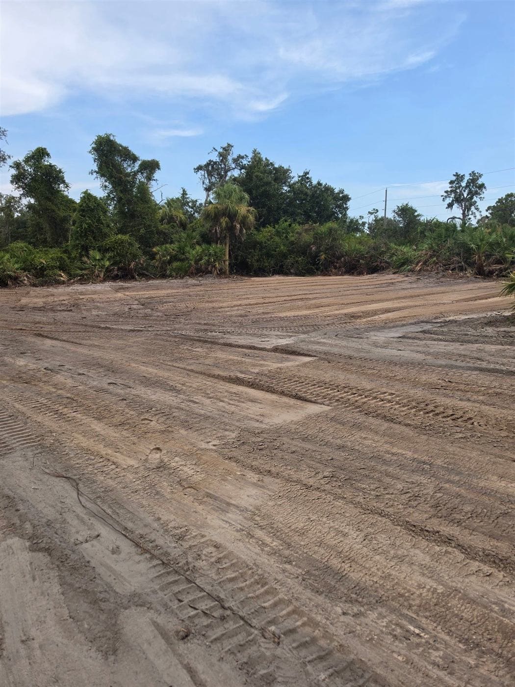 The same site cleared and graded to open dirt with equipment tracks across it.