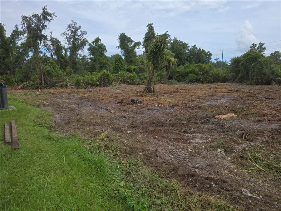 Cleared storm debris and tracked equipment marks on a residential property.